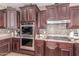 Kitchen with stainless steel double oven, gas cooktop, granite countertops, and dark wood cabinetry at 19427 W Colter St, Litchfield Park, AZ 85340