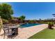 Inviting backyard pool with a waterfall feature, complemented by stylish patio furniture and desert landscaping at 19427 W Colter St, Litchfield Park, AZ 85340