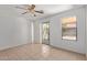 Bright bedroom features a ceiling fan, neutral tile flooring, and access to the outdoor patio at 2421 W Romley Rd, Phoenix, AZ 85041