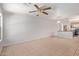 Large living room features tile and carpet flooring, ceiling fan, and open access to the kitchen with stainless appliances at 2421 W Romley Rd, Phoenix, AZ 85041