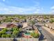Expansive aerial view of a community featuring homes with pools, solar panels, and desert landscaping under a blue sky at 3373 W Five Mile Peak Dr, San Tan Valley, AZ 85144