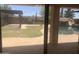 Backyard view through a sliding door showing a pool, patio, and lush landscaping at 35743 W Cartegna Ln, Maricopa, AZ 85138