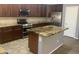Beautiful kitchen featuring an island with unique granite countertops, stainless steel appliances, and brown cabinetry at 35743 W Cartegna Ln, Maricopa, AZ 85138