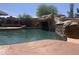 Resort-style pool with a rock slide, waterfall feature, and lush landscaping, perfect for outdoor entertaining at 35743 W Cartegna Ln, Maricopa, AZ 85138