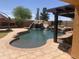 Stunning backyard pool area featuring a rock waterfall, slide, and well-maintained landscaping at 35743 W Cartegna Ln, Maricopa, AZ 85138