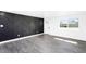 Bright living room with gray wood-look floors, a decorative accent wall, a white door, and a large window at 3850 E Ludlow Dr, Phoenix, AZ 85032