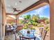 Covered back patio featuring a glass-top table, seating, and scenic view of a desert landscaped backyard at 41318 N Belfair Way, Anthem, AZ 85086