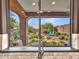 Scenic backyard view from the kitchen window, featuring lush landscaping, desert plants, and seating area at 41318 N Belfair Way, Anthem, AZ 85086