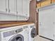 Functional laundry room equipped with front-load washer/dryer, storage cabinets, and wooden countertop at 41318 N Belfair Way, Anthem, AZ 85086