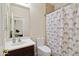 Well-lit bathroom with shower featuring patterned curtain, sink with framed mirror, and updated toilet at 43525 W Cydnee Dr, Maricopa, AZ 85138