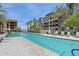 Large swimming pool with poolside loungers, palm trees, and a modern building backdrop at 5250 E Deer Valley Dr # 247, Phoenix, AZ 85054