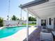 Comfortable, covered patio with a view of a sparkling blue pool, green space and shade trees at 6835 E Friess Dr, Scottsdale, AZ 85254