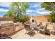 Backyard patio with built-in grill, outdoor oven, and comfortable seating area, surrounded by lush landscaping at 6862 W Honeysuckle Dr, Peoria, AZ 85383