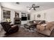 Cozy living room featuring a stone fireplace, modern ceiling fan, and hardwood flooring at 6862 W Honeysuckle Dr, Peoria, AZ 85383