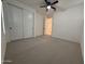 Bright bedroom features a ceiling fan, closet, and neutral carpet at 6947 W Spur Dr, Peoria, AZ 85383