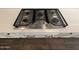 Close up of the modern kitchen cooktop with white cabinets beneath and light countertops at 6947 W Spur Dr, Peoria, AZ 85383