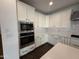 Modern kitchen featuring built-in stainless steel microwave and oven with white cabinets at 6947 W Spur Dr, Peoria, AZ 85383