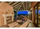 Covered outdoor living area features a stone fireplace, comfortable seating, and views of the desert landscape at 7710 E Golden Eagle Cir, Gold Canyon, AZ 85118