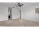 Bright bedroom with a ceiling fan, neutral carpet, and an adjacent bathroom and doorway at 8817 W Denton Ln, Glendale, AZ 85305