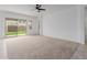 Bright living room with neutral carpet, ceiling fan, and backyard view at 8817 W Denton Ln, Glendale, AZ 85305