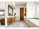 Bathroom with wood vanity, granite countertops, an oversized mirror, tiled shower, and white bathtub at 9894 E Miramonte Dr, Scottsdale, AZ 85262