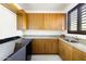Bright laundry room with wooden cabinets, granite countertops, and modern washer and dryer at 9894 E Miramonte Dr, Scottsdale, AZ 85262