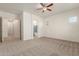 An unfurnished bedroom featuring neutral carpet, a ceiling fan, and access to the bathroom at 10502 W Bronco Trl, Peoria, AZ 85383