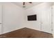 A simple bedroom with wood floors features a ceiling fan and wall-mounted TV at 10502 W Bronco Trl, Peoria, AZ 85383