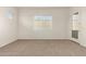 An unfurnished bedroom featuring neutral carpet, a window, and a door leading to outdoor space at 10502 W Bronco Trl, Peoria, AZ 85383