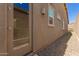 Side view of the home's stucco exterior, showing an access door and neatly arranged gravel landscaping at 10502 W Bronco Trl, Peoria, AZ 85383