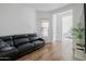 Bright living room with wood floors, black leather sofa, and a view into the bedroom at 11019 E Tiburon Ave, Mesa, AZ 85212