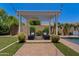 Tranquil backyard featuring a pergola with lounge chairs, artificial grass, and mature landscaping at 1500 E Sagittarius Pl, Chandler, AZ 85249