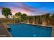 Backyard with a pristine pool, pergola with lounge chairs, lush greenery, and a basketball hoop at 1500 E Sagittarius Pl, Chandler, AZ 85249
