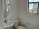 Simple bathroom with a white sink, toilet, chrome fixtures, and a circular mirror at 18001 W Lupine Ave, Goodyear, AZ 85338