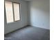 A simple bedroom space featuring neutral walls, carpet, and natural light from the window at 18001 W Lupine Ave, Goodyear, AZ 85338