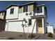 Charming two-story home with a white exterior, a two-car garage, and newly planted front yard tree at 18001 W Lupine Ave, Goodyear, AZ 85338