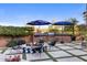 Beautiful outdoor space with cozy fire pit, a built-in grill, bar seating under umbrellas, and elegant pavers at 18127 N 98Th Way, Scottsdale, AZ 85255