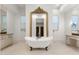 Luxurious bathroom with an elegant clawfoot tub centered under a large decorative mirror at 18127 N 98Th Way, Scottsdale, AZ 85255