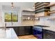 Bright kitchen features a blue range, open shelving, and a window above the sink with a backyard view at 18127 N 98Th Way, Scottsdale, AZ 85255