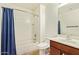 Bright bathroom featuring a tub/shower combo with a blue shower curtain and vanity with warm wood cabinetry at 25218 W Carson Ct, Buckeye, AZ 85326