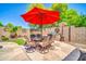 Outdoor dining area with seating for six, a red umbrella, and a built-in BBQ grill at 3214 N 138Th Dr, Avondale, AZ 85392