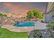 Backyard pool showcasing a rock waterfall feature, lush landscaping, and an outdoor dining area at 3214 N 138Th Dr, Avondale, AZ 85392