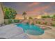 Backyard pool featuring a rock waterfall, slide, and a swim-up bar, surrounded by desert landscaping at sunset at 3214 N 138Th Dr, Avondale, AZ 85392