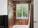 Shower and tub with travertine tile, shower curtain and plantation shutters at 3801 N Goldwater Blvd # 201, Scottsdale, AZ 85251