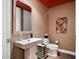 Stylish powder room featuring a pedestal sink, decorative mirror, and colorful wall art at 3801 N Goldwater Blvd # 201, Scottsdale, AZ 85251