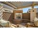Outdoor fireplace in a shaded patio area, featuring comfortable seating and a pergola at 3801 N Goldwater Blvd # 201, Scottsdale, AZ 85251