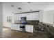 Bright kitchen with white cabinets, stainless steel appliances, granite countertops, and wood-look floors at 41839 W Avella Dr, Maricopa, AZ 85138