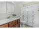 Bathroom features a vanity with wood cabinets and white countertops, toilet and shower with curtains at 6051 E Ensenada St, Mesa, AZ 85205