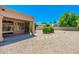 A covered patio extends to a gravel yard with stone accents and mature landscaping for outdoor enjoyment at 6180 W Oraibi Dr, Glendale, AZ 85308