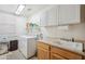 Bright laundry room features a washer, dryer, sink, white cabinets, and shelving for storage at 6827 W El Cortez Pl, Peoria, AZ 85383